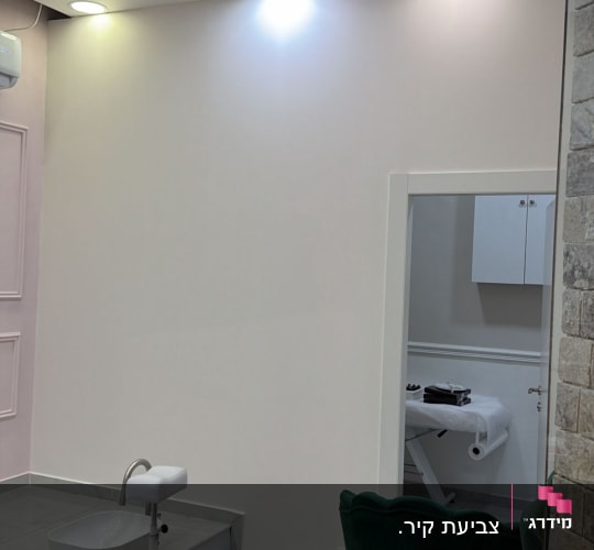 חדר עם קיר צבוע, כיסאות וכלי עבודה לצביעה